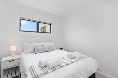 a white bedroom with a bed with towels on it at Beach Break Two in Cape Town