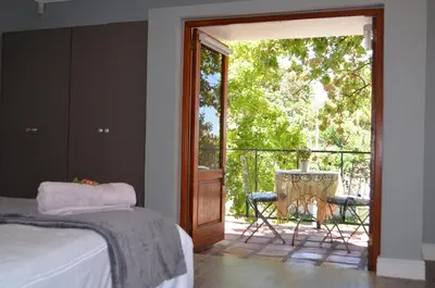 a bedroom with a door open to a patio with a table at Gatsby Suite, with pool in quiet area, close to town in Stellenbosch