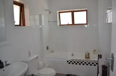 a white bathroom with a toilet and a sink at Gatsby Suite, with pool in quiet area, close to town in Stellenbosch