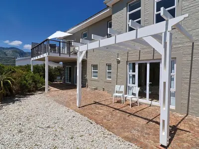 a white pergola in front of a house at Penguin View in Bettyʼs Bay