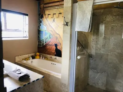 a bathroom with a tub and a shower with a sink at Listening Wind Self-Catering accommodation in Bettyʼs Bay