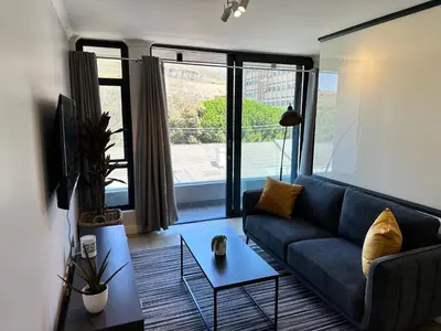 a living room with a blue couch and a large window at The Westwood Deluxe Studio in Cape Town
