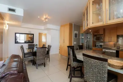 a kitchen and living room with a table and chairs at 1401 Hibernian Towers Luxury Self Catering Apartment Strand Western Cape South Africa in Cape Town