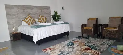 a bedroom with a bed and two chairs and a table at Matt's Place in Cape Town