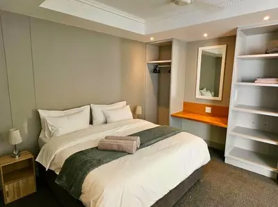 a bedroom with a large white bed and a mirror at Central - Whale Watching Paradise -Self check in in Hermanus