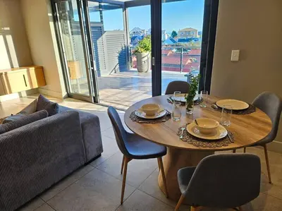a table and chairs in a living room with a couch at Central - Whale Watching Paradise -Self check in in Hermanus