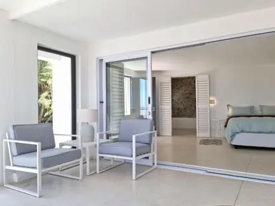 a bedroom with a bed and two chairs at 'Kaya Moya' - Luxury Suite for 2 with Ocean Views in Gordonʼs Bay