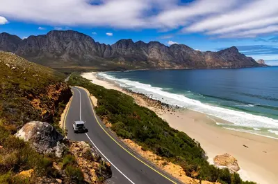 a road next to a beach with a truck on it at 'Kaya Moya' - Luxury Suite for 2 with Ocean Views in Gordonʼs Bay