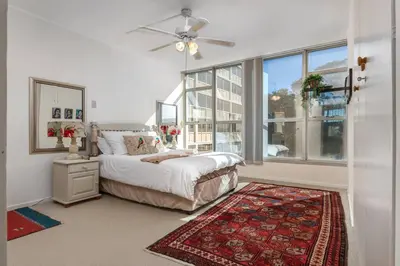 a bedroom with a bed and a large window at Elegance on Beach in Cape Town