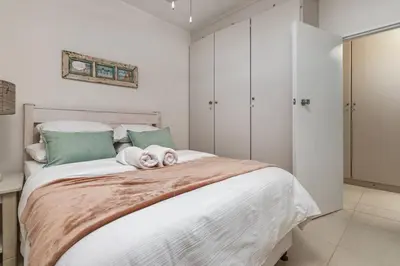a bedroom with a bed with a dog laying on it at Elegance on Beach in Cape Town