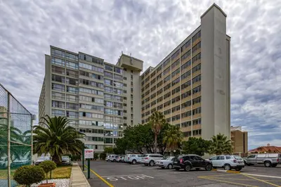 a large building with cars parked in a parking lot at Elegance on Beach in Cape Town