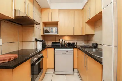 a small kitchen with wooden cabinets and a dishwasher at 506 Hibernian Towers Luxury Self Catering Apartment Strand Cape Town South Africa in Cape Town