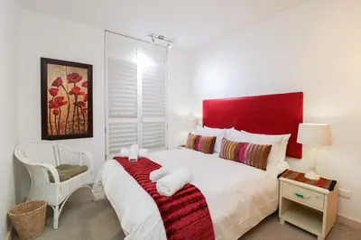 a bedroom with a large bed with a red headboard at 506 Hibernian Towers Luxury Self Catering Apartment Strand Cape Town South Africa in Cape Town