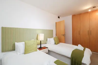 a hotel room with two beds and a cabinet at 506 Hibernian Towers Luxury Self Catering Apartment Strand Cape Town South Africa in Cape Town