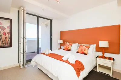 a bedroom with a large bed and a large window at 506 Hibernian Towers Luxury Self Catering Apartment Strand Cape Town South Africa in Cape Town