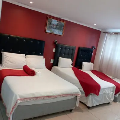 two beds in a hotel room with red walls at Sunshine Guest House in Cape Town