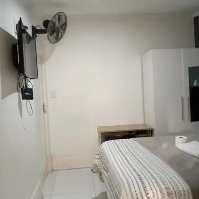 a bedroom with a bed and a fan on the wall at Sunshine Guest House in Cape Town
