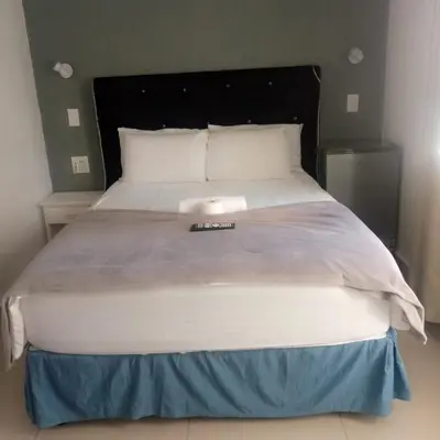 a large bed in a bedroom with a white bedspread at Sunshine Guest House in Cape Town