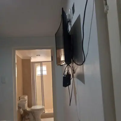 a bathroom with a toilet and a television on a wall at Sunshine Guest House in Cape Town