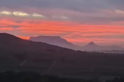 a view of a sunset with mountains in the background at Devon View Olive Farm in Stellenbosch