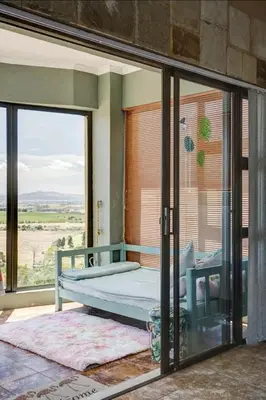 a bedroom with a bed and sliding glass doors at Devon View Olive Farm in Stellenbosch