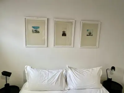 three pictures on a wall above a bed with white pillows at 2 Bedroom Apartment On Dorp St - Prime Location in Stellenbosch