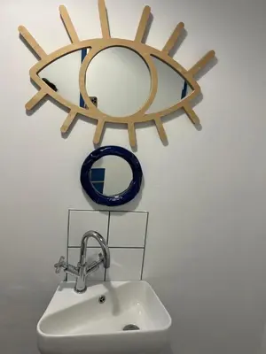 a bathroom sink with a mirror and a sun on the wall at 2 Bedroom Apartment On Dorp St - Prime Location in Stellenbosch