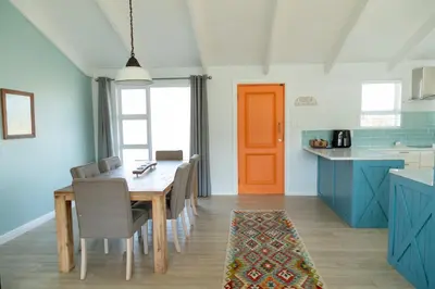 a kitchen with a table and chairs and a orange door at Fijnbos in Pringle Bay