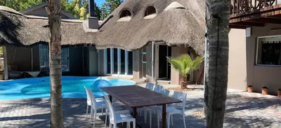 a table and chairs in front of a house with a pool at STAY In TEHAMA in Cape Town