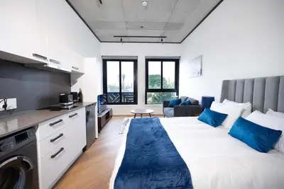a bedroom with a large bed with blue pillows at Bridgewater Studio Apartment in Century City