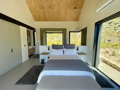 a bedroom with two beds and large windows at The Unbound - Escape the Ordinary in Romansrivier