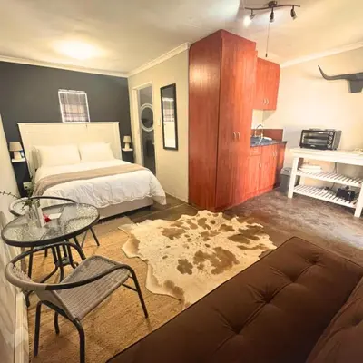 a bedroom with a bed and a table and a couch at Helpmekaar in Wellington