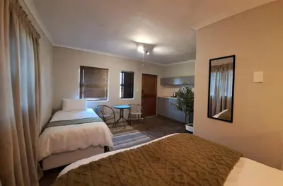 a hotel room with two beds and a table at Helpmekaar in Wellington