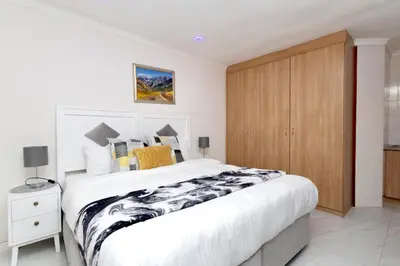 a bedroom with a large bed and a wooden cabinet at Serena inn Room 1 in Cape Town