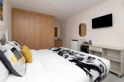a bedroom with a large bed with a tv on the wall at Serena inn Room 1 in Cape Town