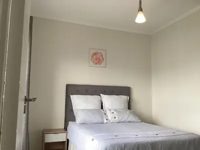 a bedroom with a bed with white sheets at Smartstay Apartments The Sandown in Cape Town
