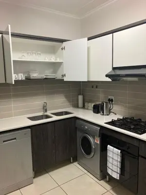 a kitchen with a stove and a washing machine at Smartstay Apartments The Sandown in Cape Town