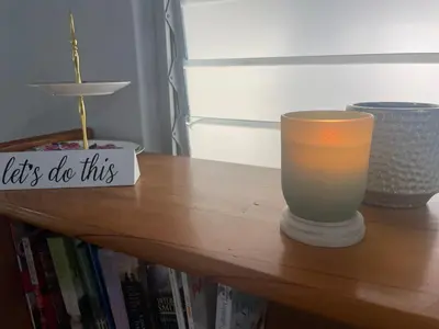 a table with a candle on top of a book shelf at Lente Beach Cottage, Fleur Park, Gordon's Bay in Gordonʼs Bay