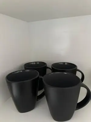 four black coffee cups sitting on a shelf at Sleek Modern Luxury Pool Side Apartment in Cape Town