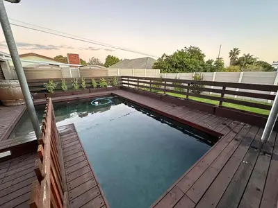 a pool of water on a wooden deck with a fence at Sleek Modern Luxury Pool Side Apartment in Cape Town