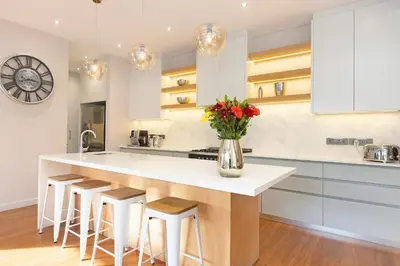 a kitchen with white cabinets and a counter with stools at Sunset Serenity Villa in Cape Town