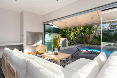 a living room with white furniture and a swimming pool at Sunset Serenity Villa in Cape Town