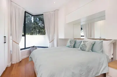 a white bedroom with a large bed and a window at Sunset Serenity Villa in Cape Town