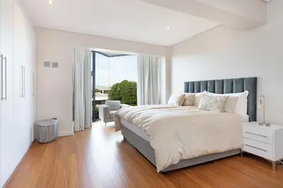 a white bedroom with a large bed and a window at Sunset Serenity Villa in Cape Town