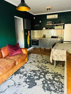 a living room with a couch and a kitchen at Beautiful garden flat in Cape Town