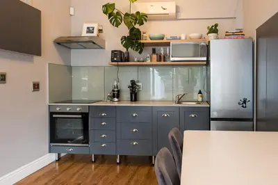 a kitchen with blue cabinets and a refrigerator at Beautiful garden flat in Cape Town