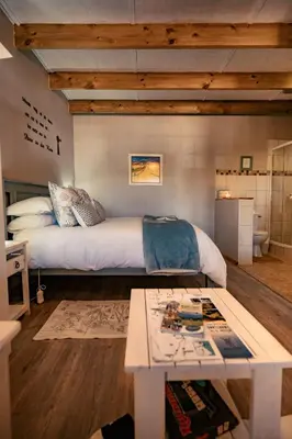a bedroom with a large bed and a table at Dassenheuwel Farm Stay Cottages in Malmesbury