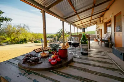 a wooden table with wine glasses and food on it at Dassenheuwel Farm Stay Cottages in Malmesbury