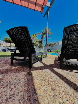 two benches sitting next to a swimming pool at Private garden guest house in Cape Town