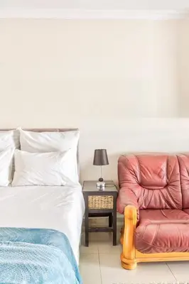 a bedroom with a bed and a red chair at Goodwood Oasis Free WiFi-Parking 2 in Cape Town